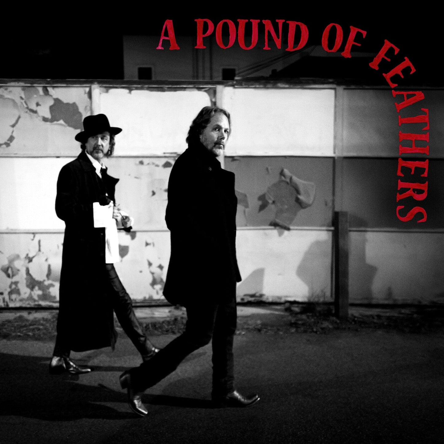 Black and white photo of two men walking, album cover art.