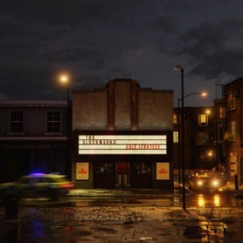 Nighttime view of a brick theater with a glowing marquee and wet street.