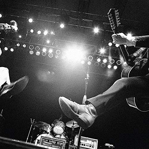 Black and white concert photo of a musician jumping with a guitar.
