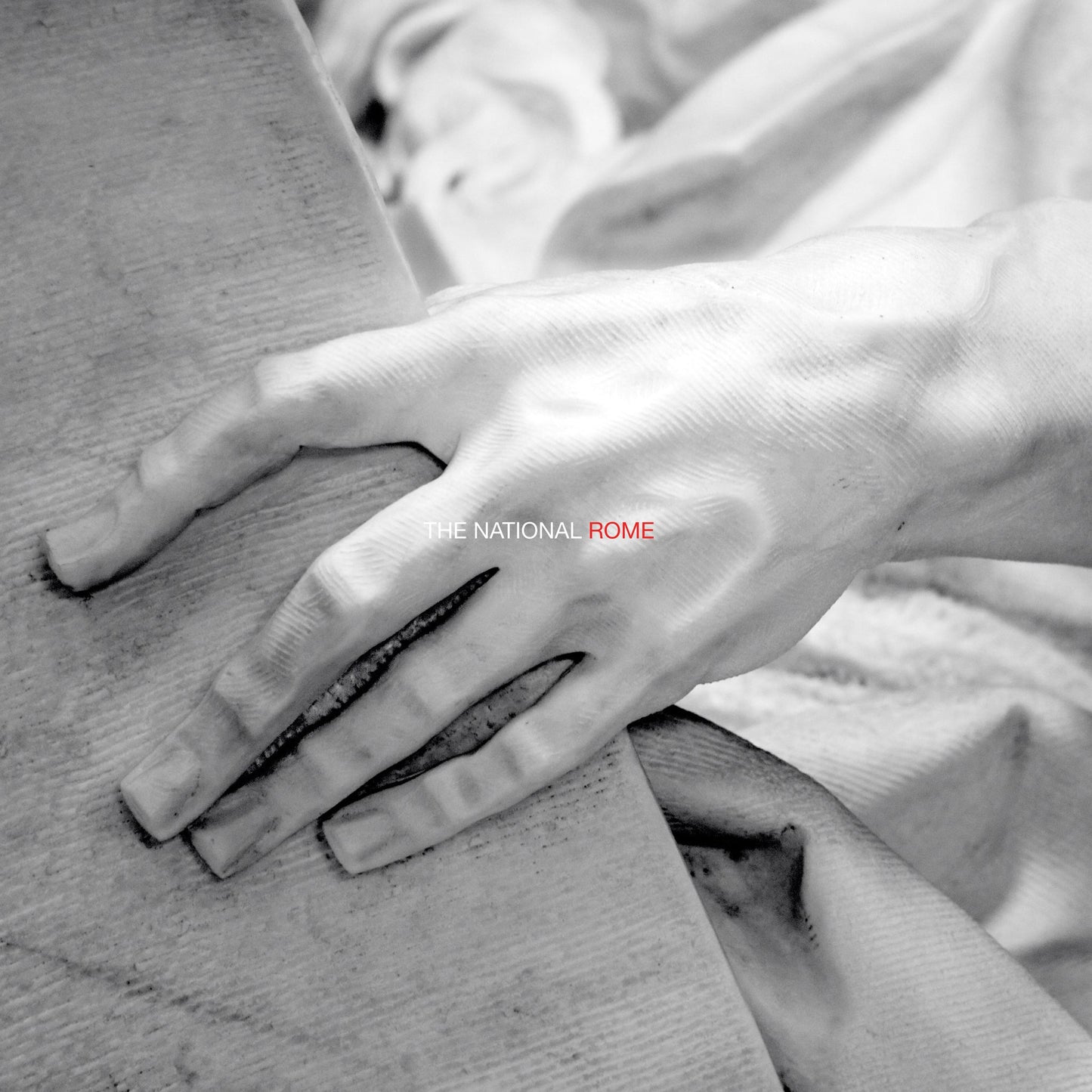 Black and white photo of a hand on stone, album cover for The National’s Rome.