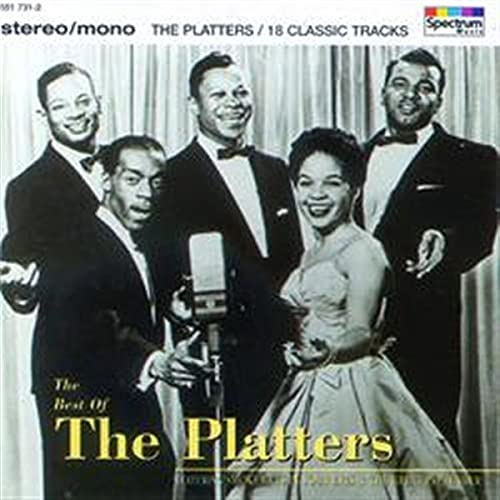Black and white photo of The Platters singing in formal attire before a microphone.