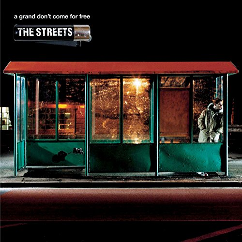 A man stands inside a dark, green and red bus shelter at night.