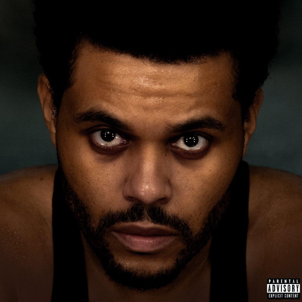 Close-up portrait of The Weeknd with intense gaze, dark hair, and beard.