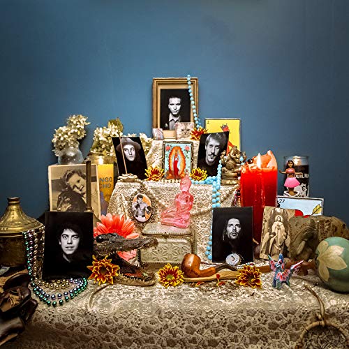 A table with a lace cloth, adorned with portraits, flowers, and religious figurines.