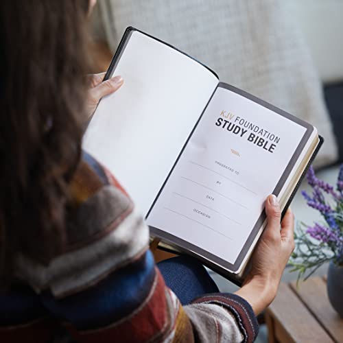 A person holds an open KJV Foundation Study Bible showing a presentation page.