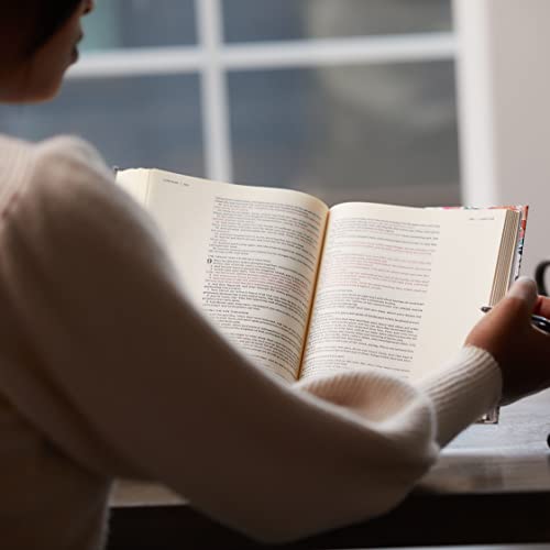 Open Bible with lined pages, held by a person near a window.