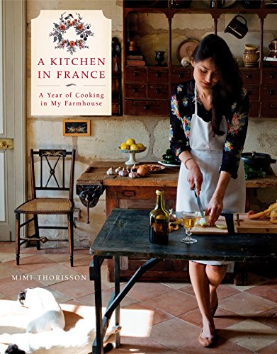 Cookbook cover with a woman preparing food in a rustic French kitchen.