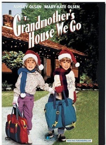 Two young girls with Santa hats and bags in front of a house.