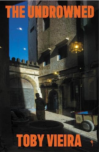 Book cover featuring a man standing in a dimly lit, stone-walled courtyard at dusk.