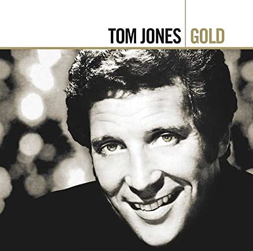 Black and white portrait of Tom Jones smiling with blurred lights in the background.