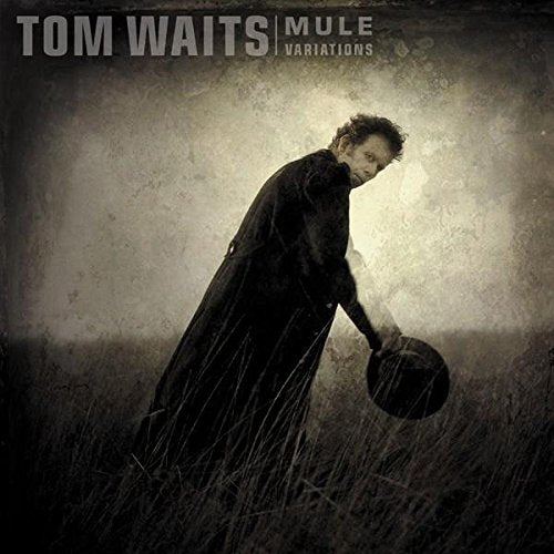 Tom Waits in a long coat holding a hat in a field, sepia-toned album cover.