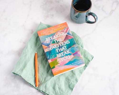 Book cover with colorful abstract design, pen, and coffee mug.