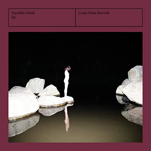 A CD cover featuring a person standing on rocks by dark water at night.