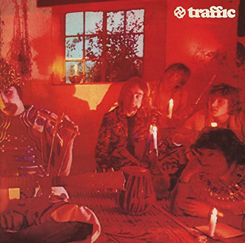 The band Traffic in a red-lit room with candles and a window.