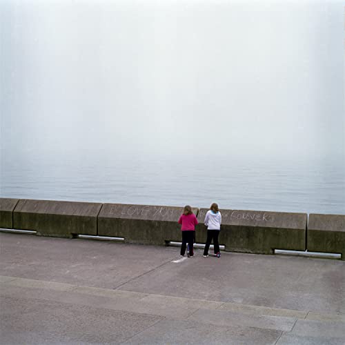 Album cover: Two figures stand on a concrete seawall in fog.