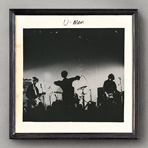 Black and white photo of a band performing on a stage, framed.