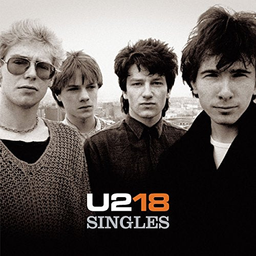"Black and white image of U2 band members with 'U218 Singles' text below."