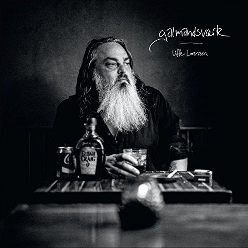 Black and white portrait of a bearded man with drinks and cigarettes.