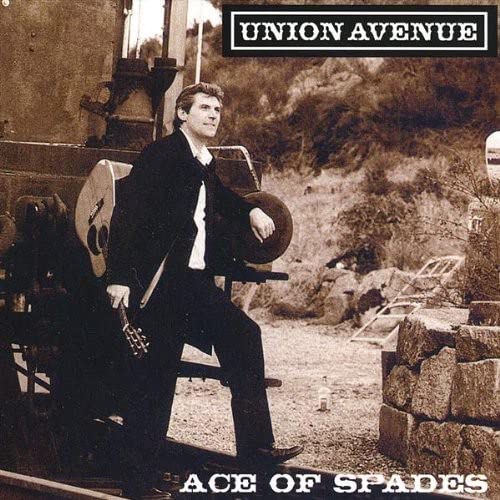 CD cover: man with guitar seated near a train, sepia tone.