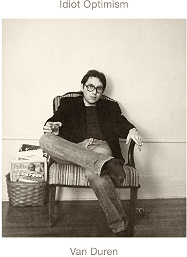 Black and white portrait of a man sitting in a striped chair.