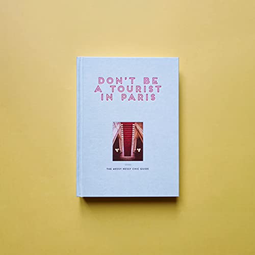 Pale blue book cover with pink text: "Don't Be A Tourist in Paris".