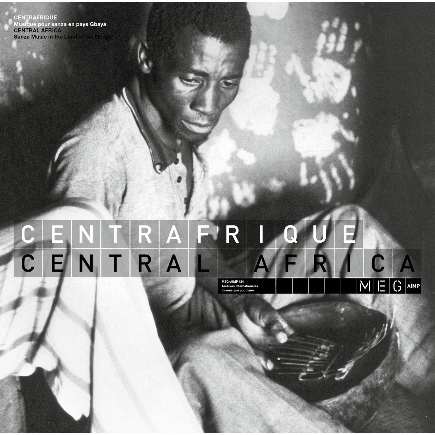 Black and white photo of a man playing a sanza instrument in Central Africa.