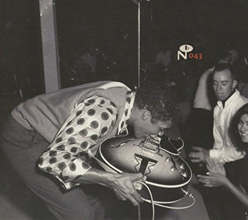 Black and white photo of a man kissing his electric guitar on stage.