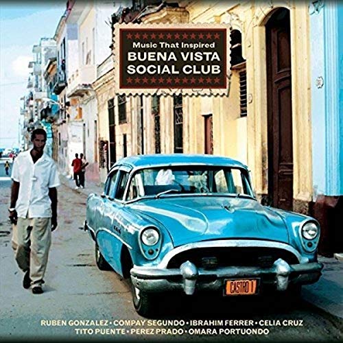 A man walks on a street past a bright blue vintage car in Cuba.