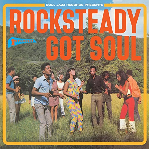 Album cover: group of people in colorful clothing in a field.