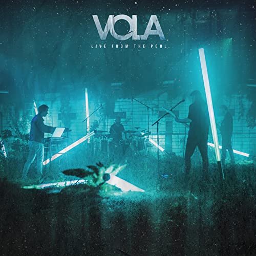 The band VOLA performing live in a pool lit by bright teal neon lights.