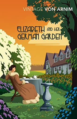 A woman in a brown coat sits at a garden table near a house.