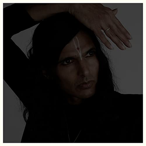 Close-up portrait of a person with long dark hair and facial markings.