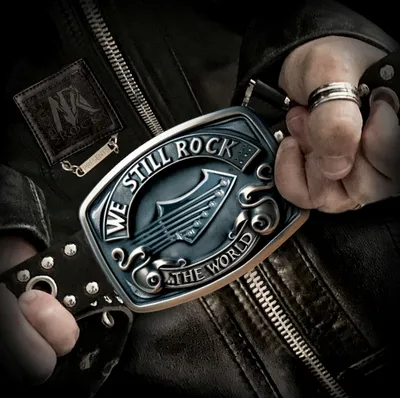 Close-up of a silver belt buckle reading "We Still Rock the World.