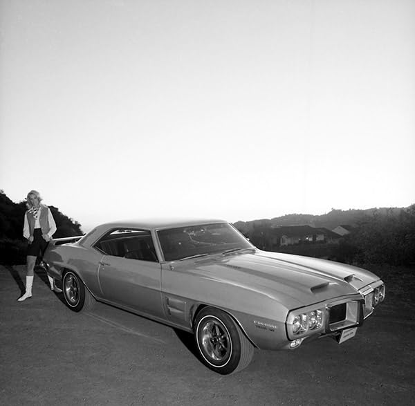 Black and white photo of a classic American muscle car with a person.
