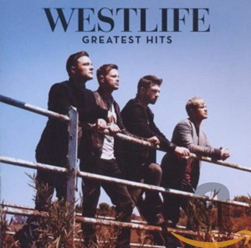 The four members of Westlife leaning against a metal fence against a blue sky.