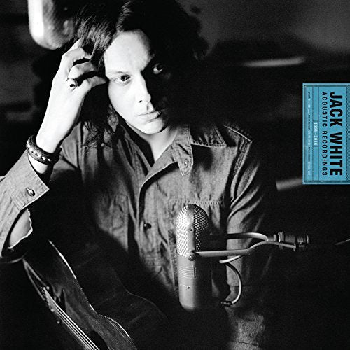 Black and white portrait of Jack White with an acoustic guitar and vintage microphone.