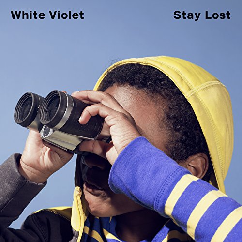 A person in a yellow hoodie looks through binoculars against a clear blue sky.