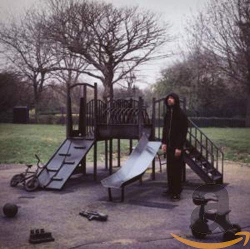 Hooded figure stands near a playground in a bleak, wintry landscape.