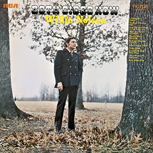 Willie Nelson stands in a park between two trees on this album cover.