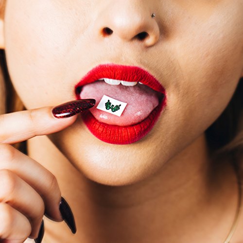 Close-up of a person with a small, patterned square on their tongue.