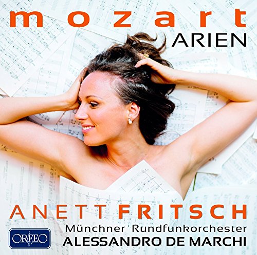 A woman lies on sheet music, smiling, with hands in her hair.