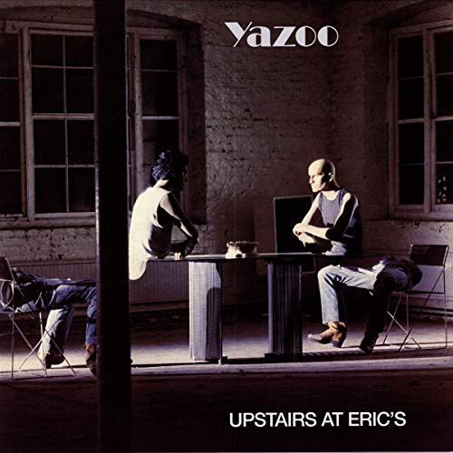 Two people sit at a table in a dimly lit room, album cover art.