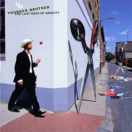 Man in suit walks toward giant scissors on a city street.