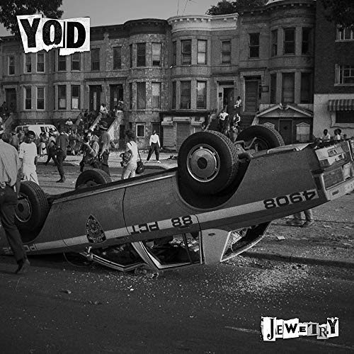 Black and white album cover featuring an overturned car in a city street.