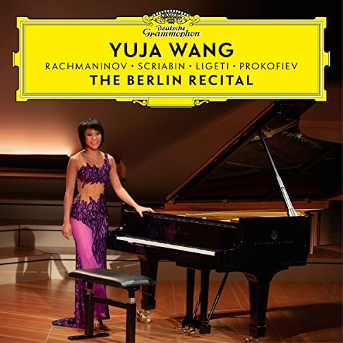 Pianist Yuja Wang in a purple gown standing beside a grand piano on stage.