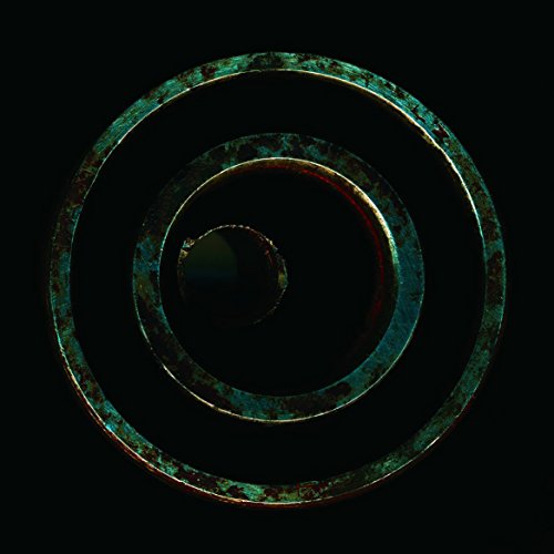 Concentric, corroded metal rings against a dark background.