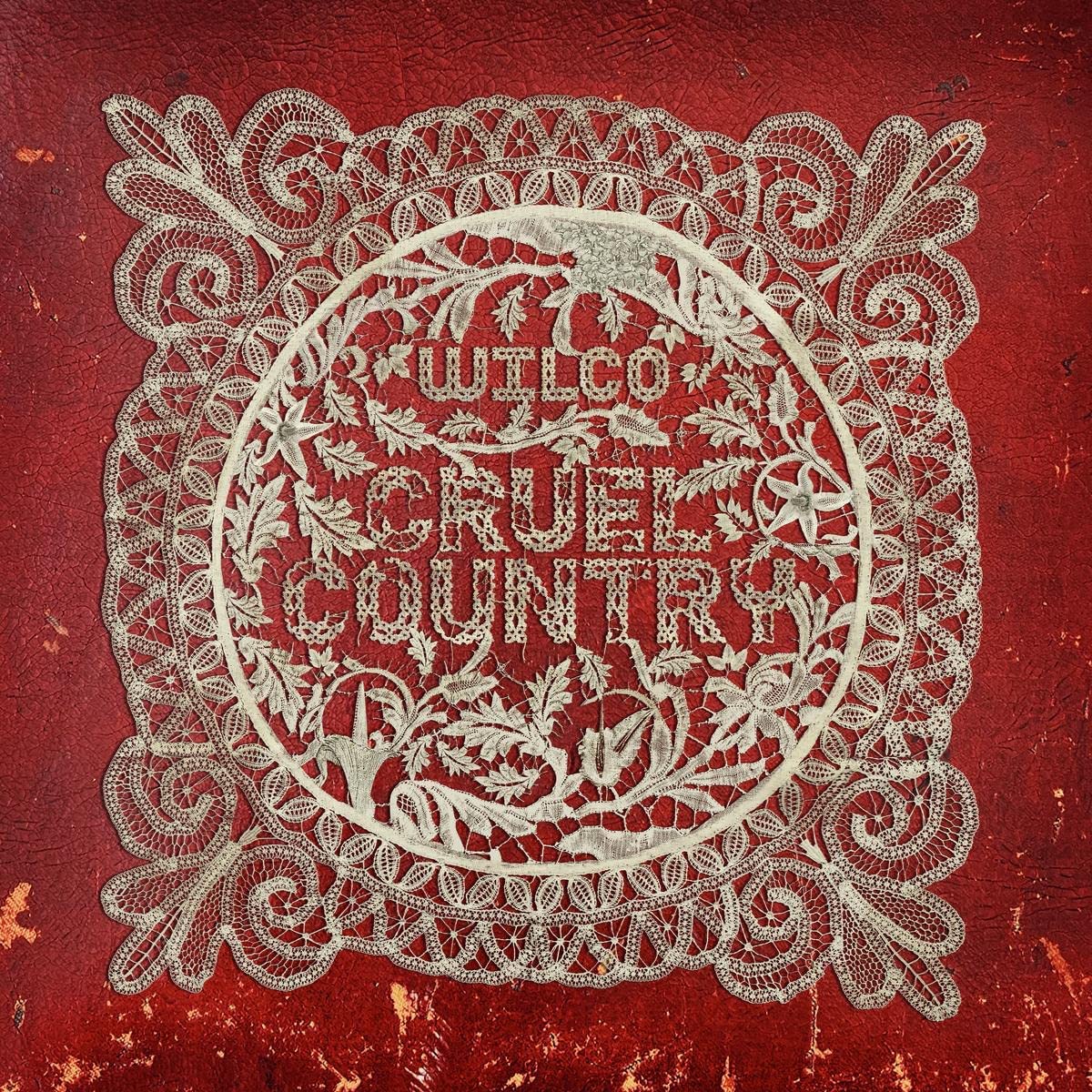 "Red textured album cover with 'Wilco Cruel Country' in ornate white lace design."