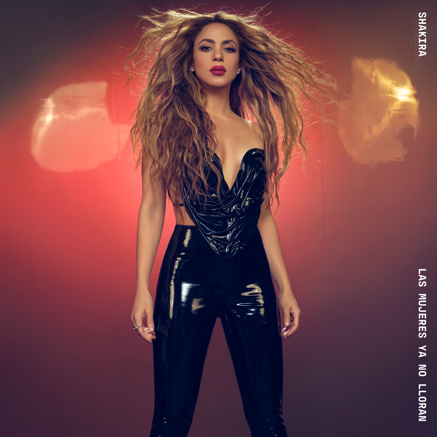 Shakira in a black latex outfit, long wavy hair, looking at the viewer.