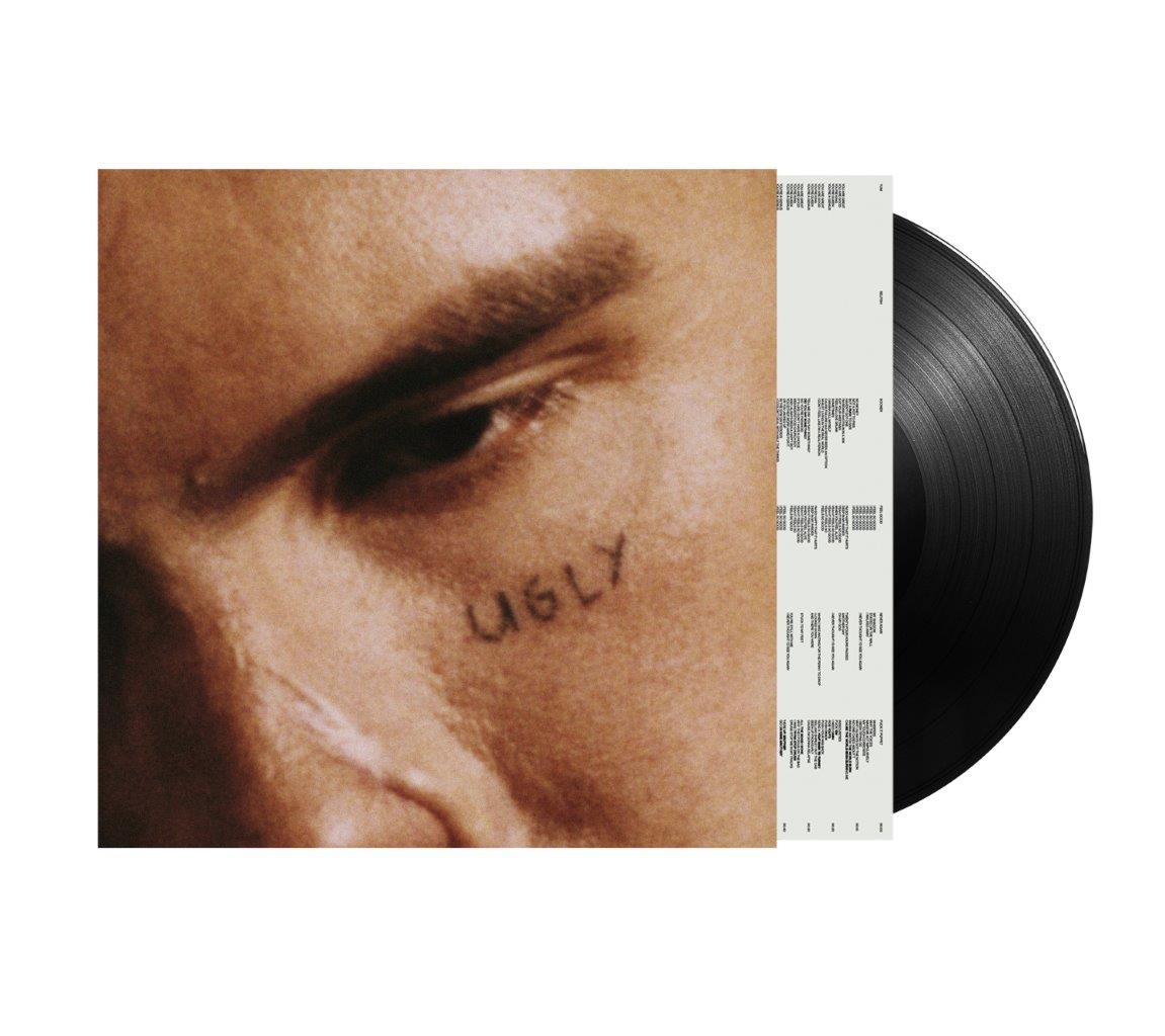 "Vinyl record with cover art featuring a close-up of a man's face with 'UGLY' written."