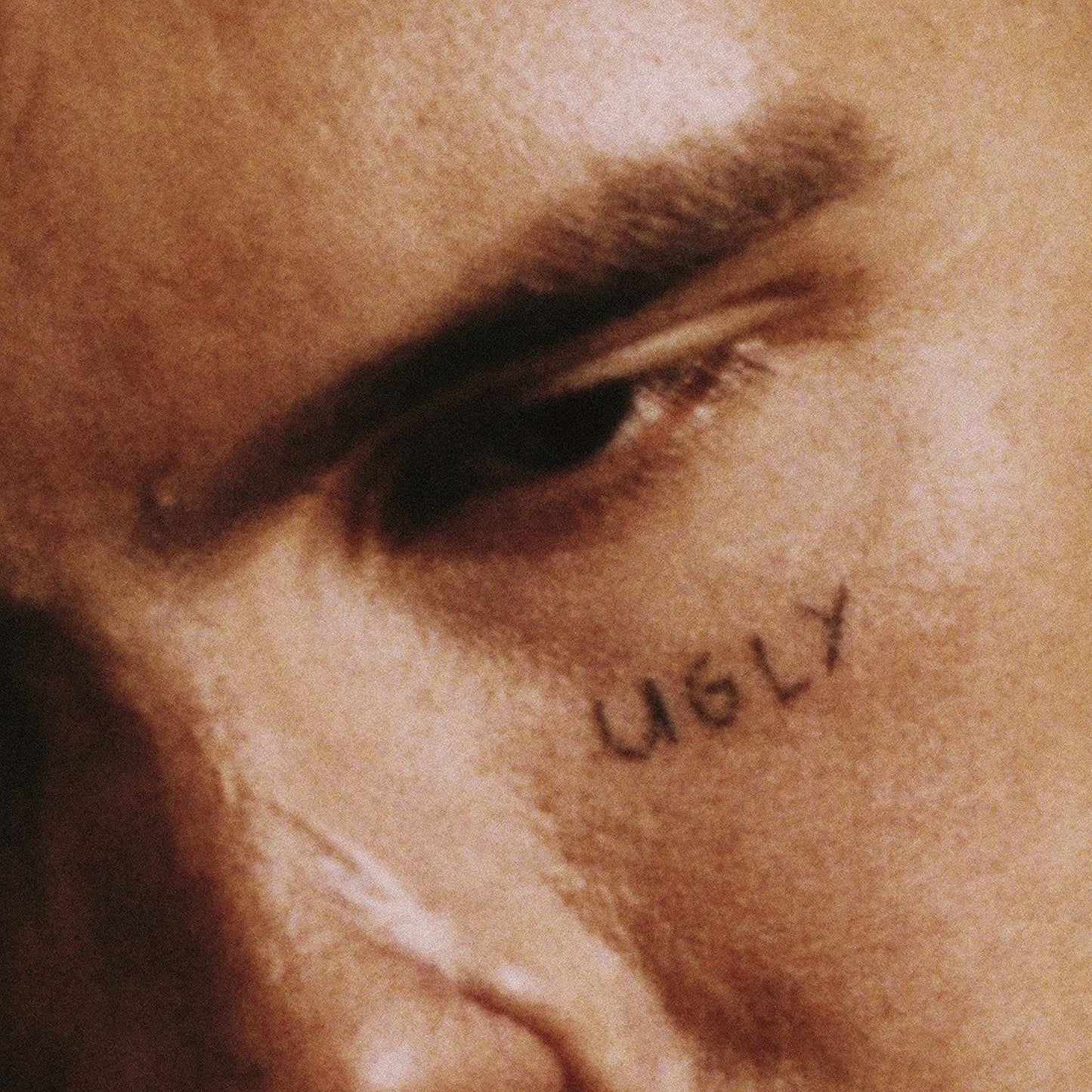 A close-up of a person's face with "UGLY" written below their eye.